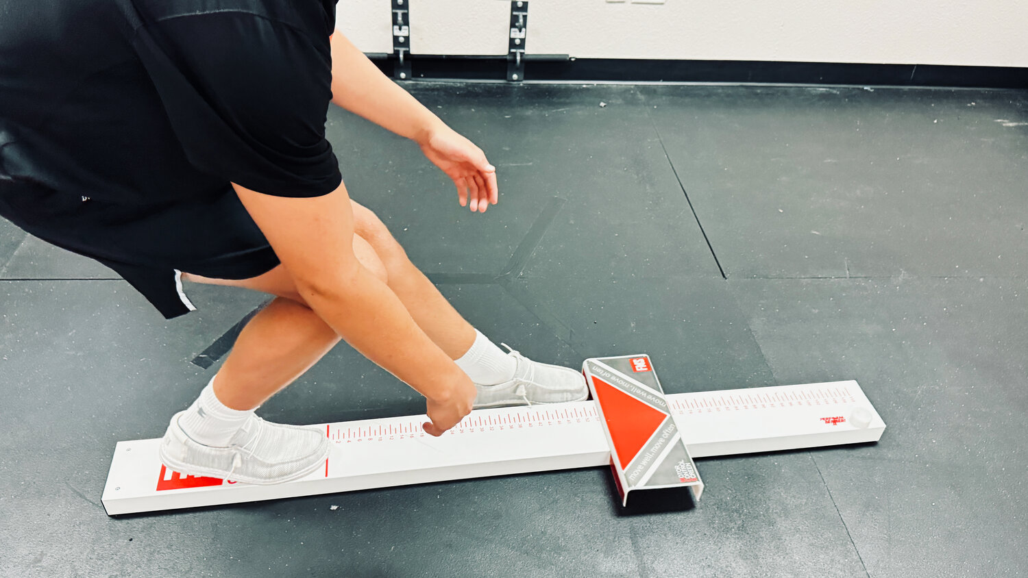 Golfer performing the FMS Motor Control Screen single-leg reach test on a measuring beam at a Fort Worth golf-performance clinic