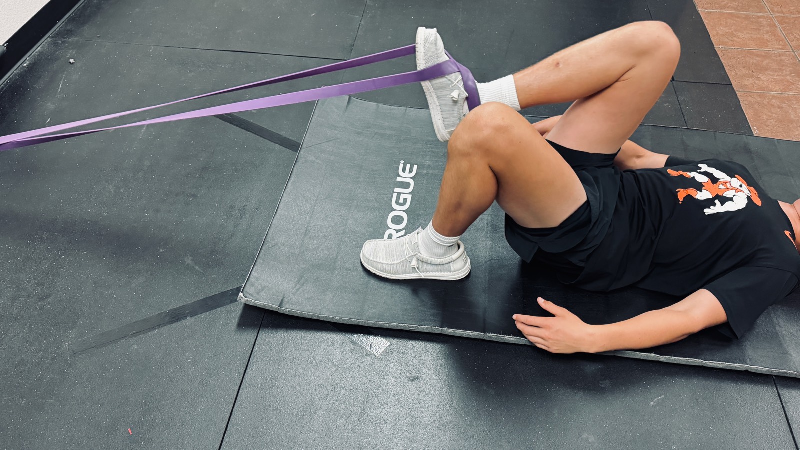 Banded triple-flexion corrective exercise on the floor at a Fort Worth sports chiropractic clinic