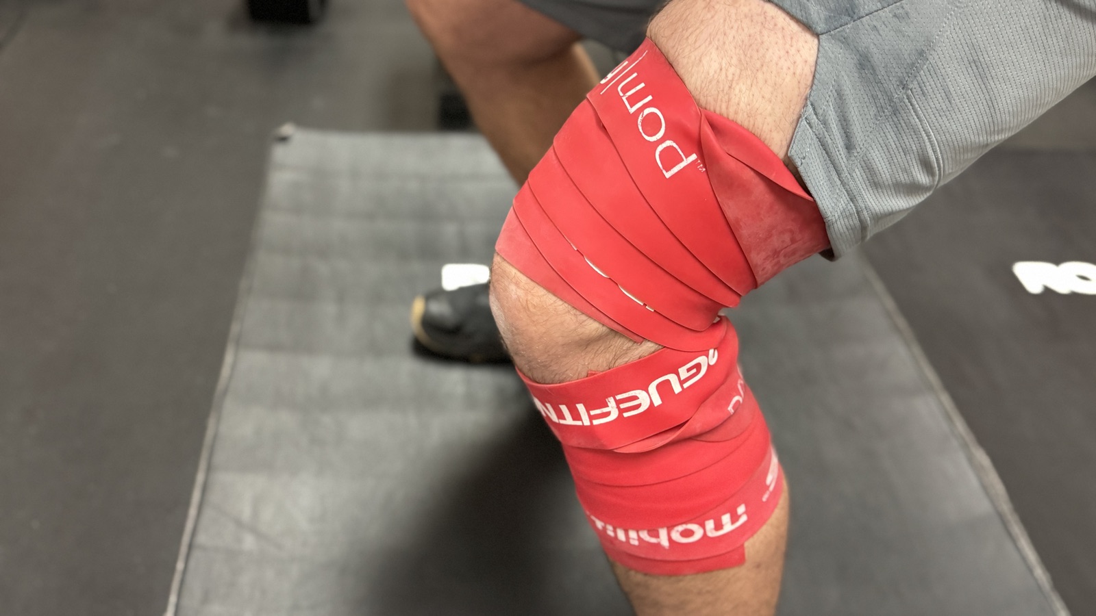 Voodoo floss compression band wrapped around an athlete's knee for mobility at a Fort Worth sports chiropractic clinic